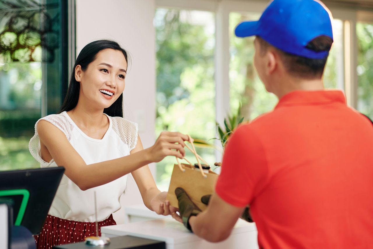 Smiling business owner handing an order to a customer
