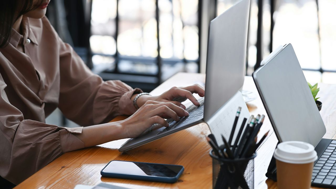 Business owner typing on a laptop in a bright office