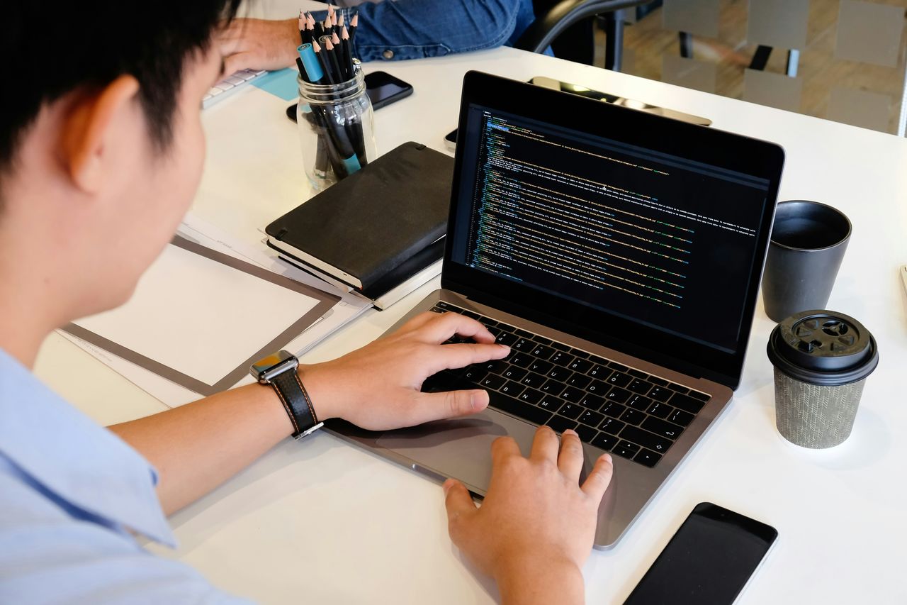 Web developer writing code on a laptop at a desk