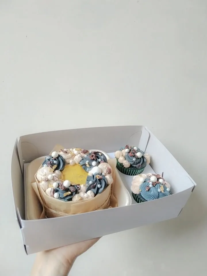 A dusty blue bento cake with two matching cupcakes